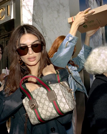Emily Ratajkowski wearing sunglasses and holding a Gucci GG monogram handbag outdoors for an ad campaign.