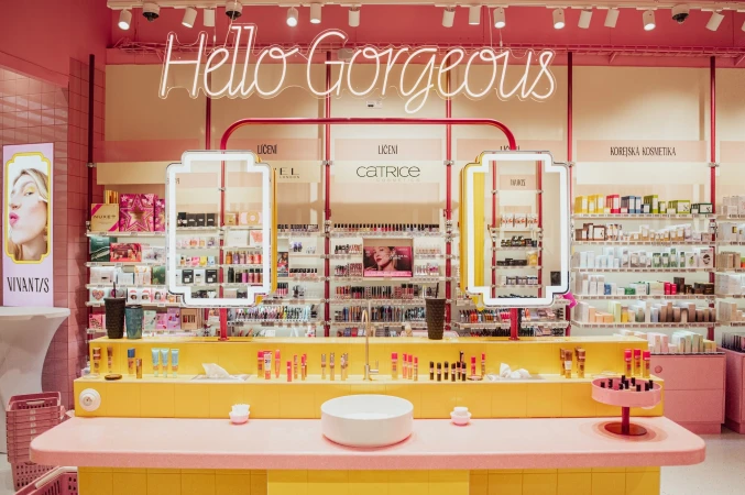 Bright pink and yellow retail store interior with cosmetics displays and illuminated Hello Gorgeous neon sign