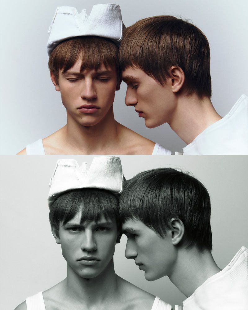 Portrait of two young adult men with close proximity, one wearing a fabric crown, in a studio shot with a neutral background.