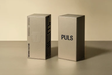 Two metallic rectangular packaging boxes with typography on a neutral surface