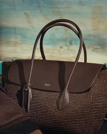 Brown leather and woven tote bag by Ferragamo against a painted seaside backdrop