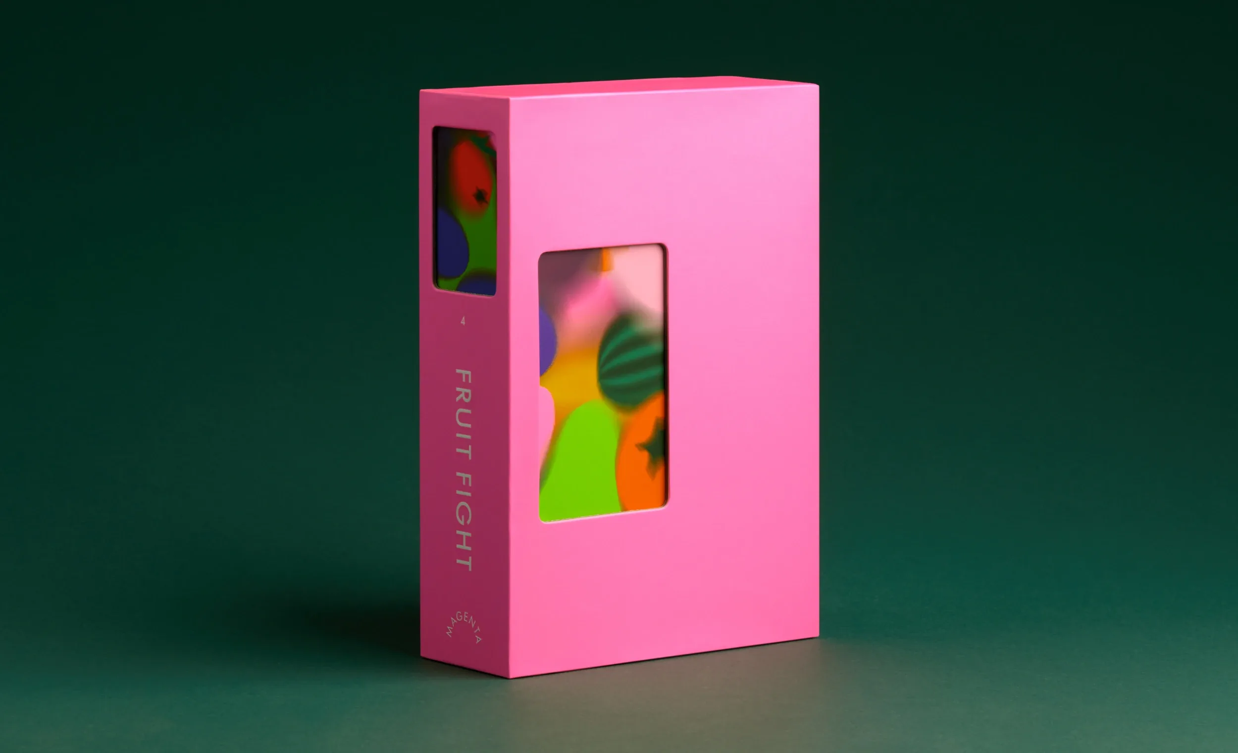 Vibrant pink packaging box with rectangular cutouts revealing colourful abstract graphics against a dark green studio background