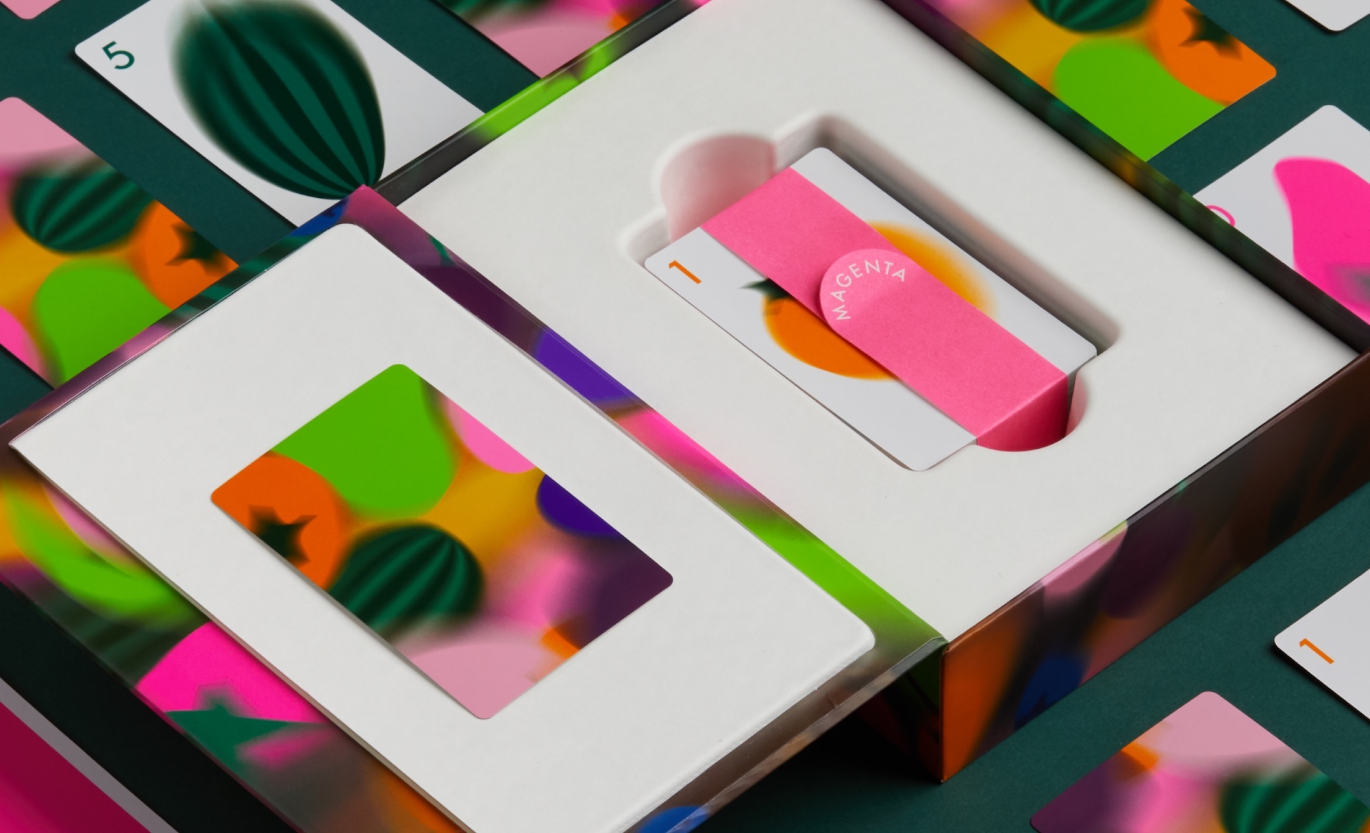 Custom product packaging box containing colourful illustrated playing cards with a pink paper band for CMYK brand identity