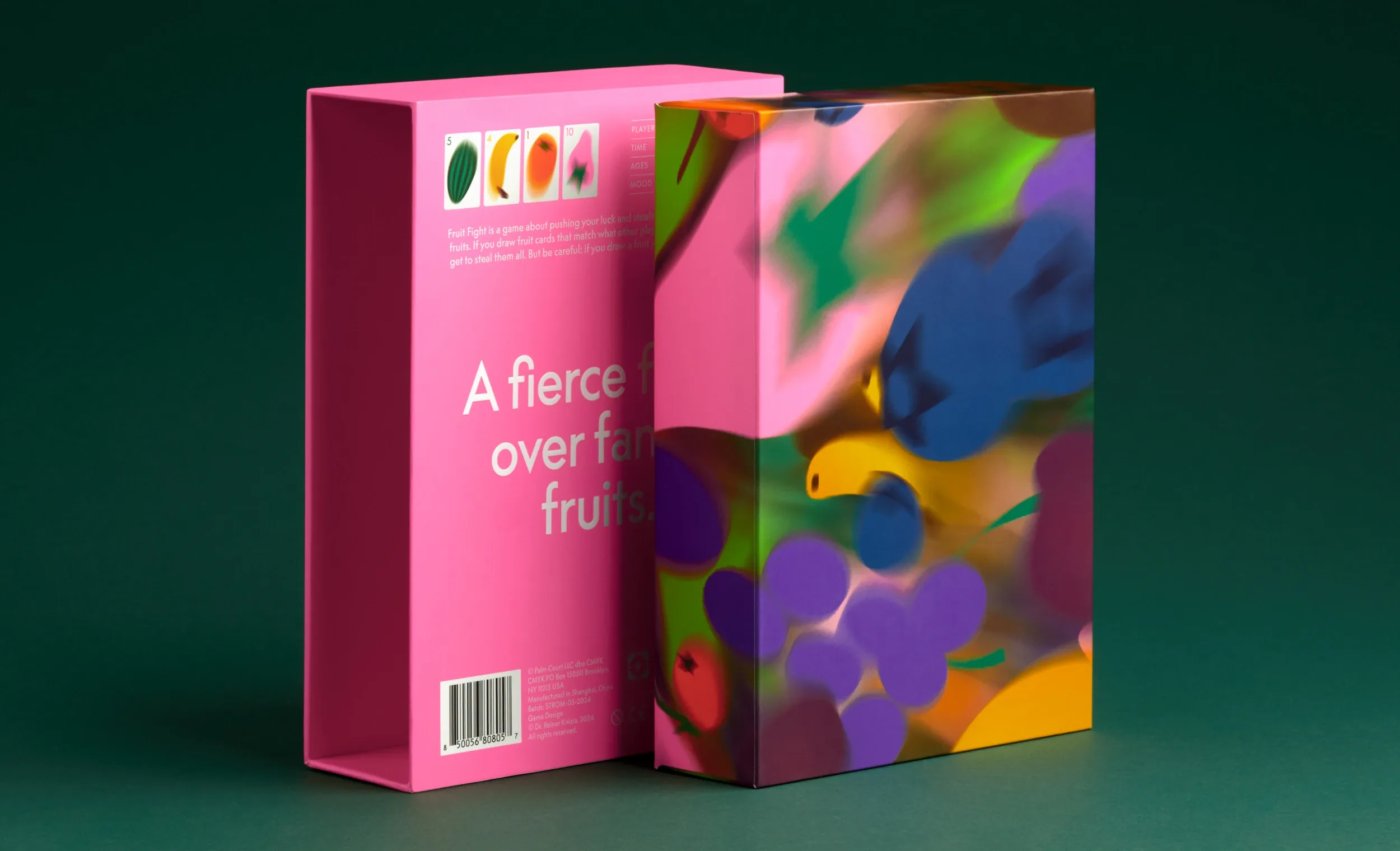 A bright pink packaging box with colourful abstract fruit illustrations standing on a dark green surface.