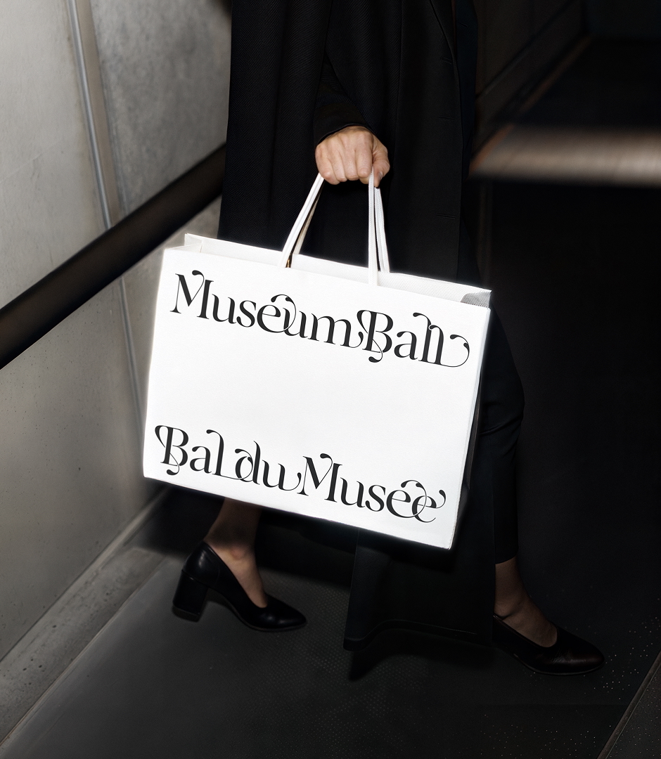 Person holding a white shopping bag with bold typography against a dark staircase