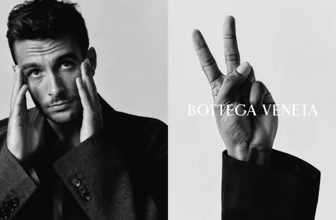 Black and white portrait of a man touching his temples beside a raised hand showing a peace sign and Bottega Veneta text.