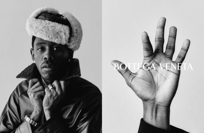 Tyler, the Creator wearing a shearling ushanka hat and leather jacket next to a hand raised with Bottega Veneta text