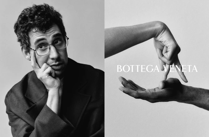 Jack Antonoff wearing glasses in a dark jacket with hands gesturing against a white background for Bottega Veneta campaign
