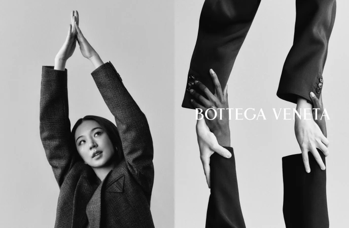 Black and white editorial image for Bottega Veneta featuring a woman posing in a tailored blazer against a plain background