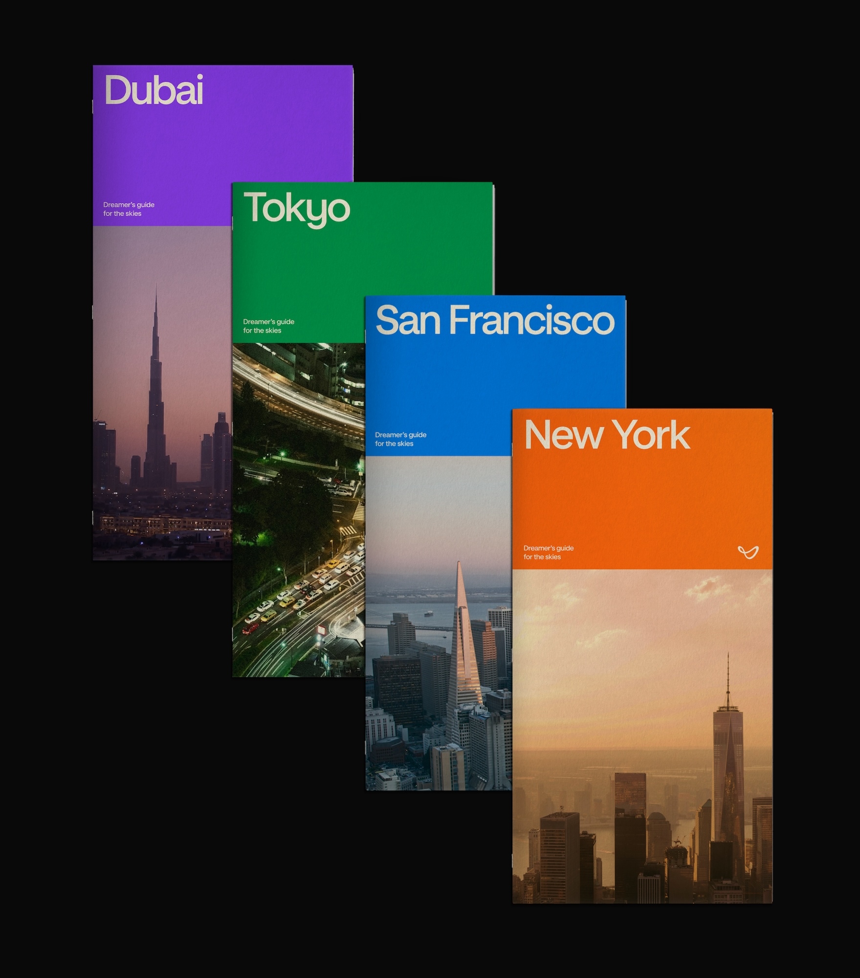 Four vertical city guide booklets titled Dubai, Tokyo, San Francisco, and New York arranged diagonally against a black background.