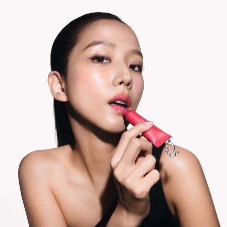 Jisoo applying pink lip product against a white background for Dior Spring 2025 campaign