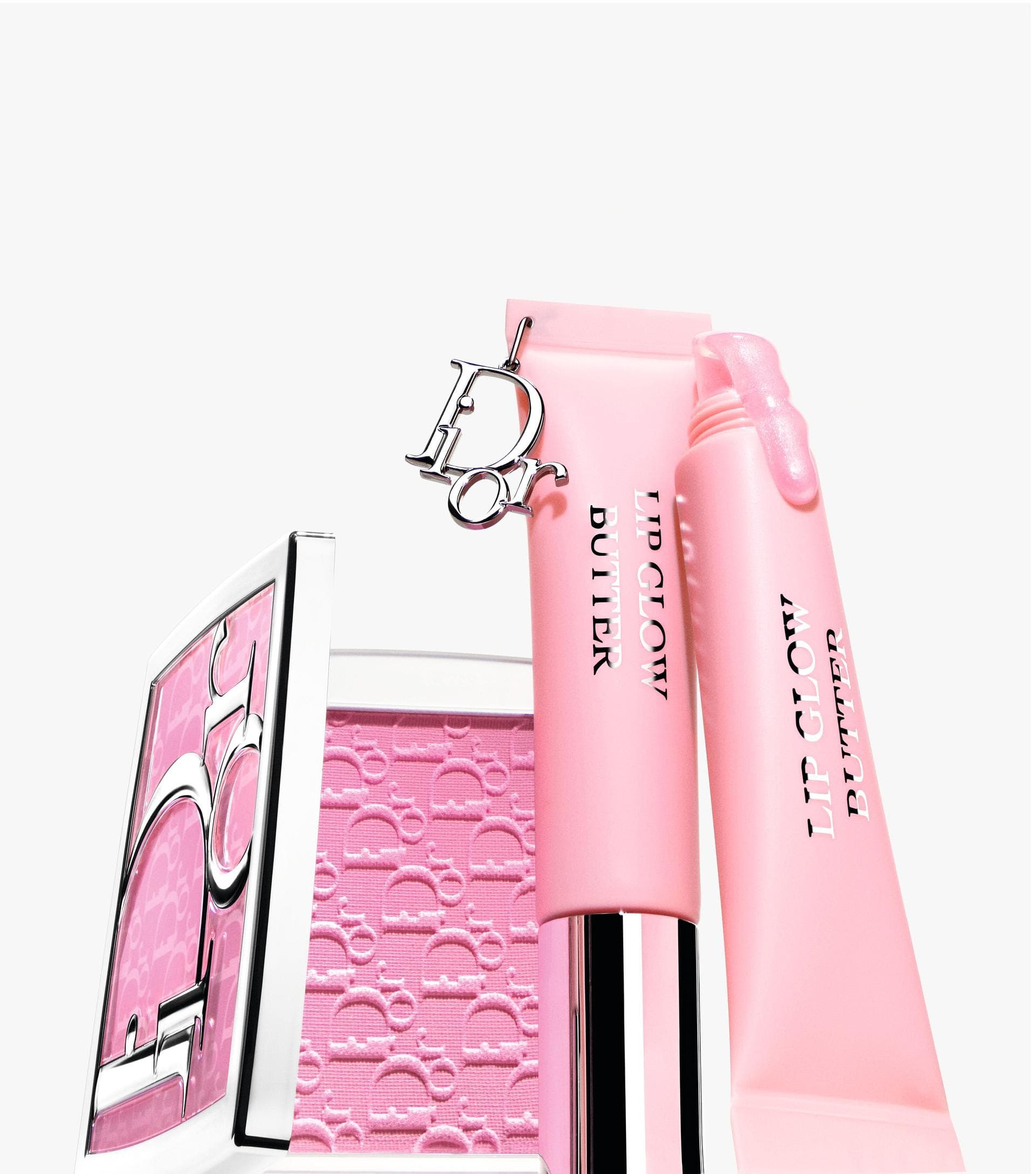 Pink Dior lip butter tubes and a compact case featuring the iconic monogram logo against a clean white seamless background.