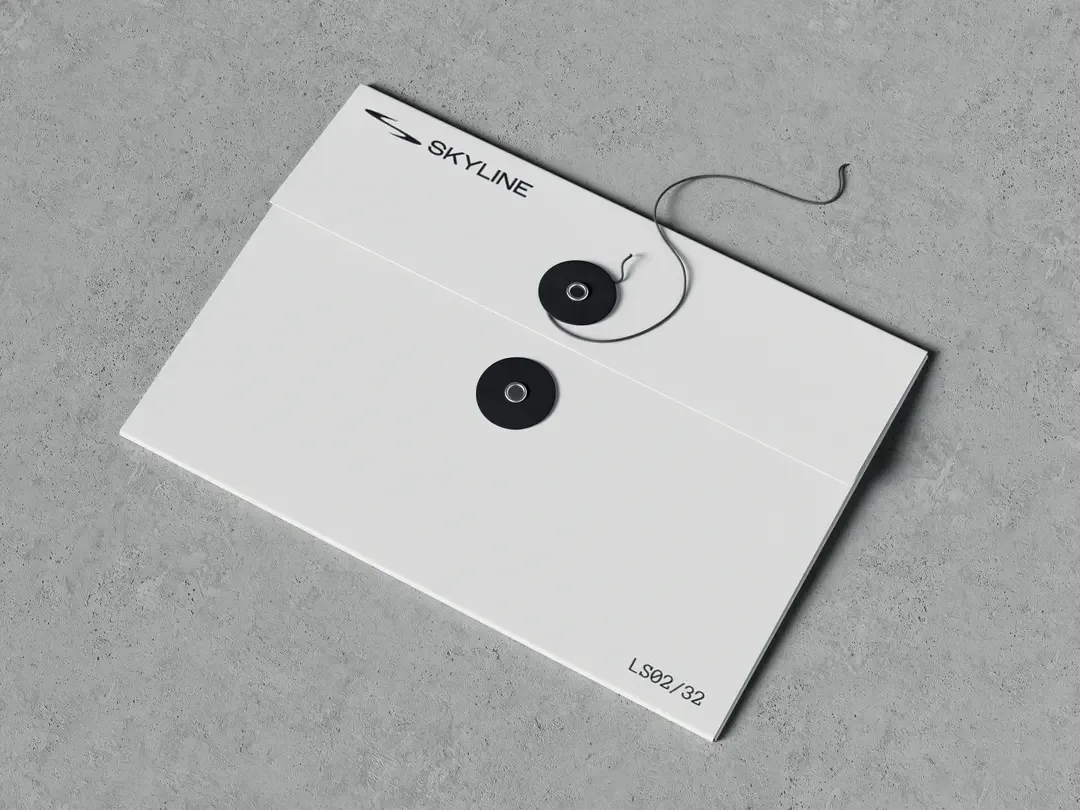 White string and button envelope with Skyline logo resting on grey concrete textured background