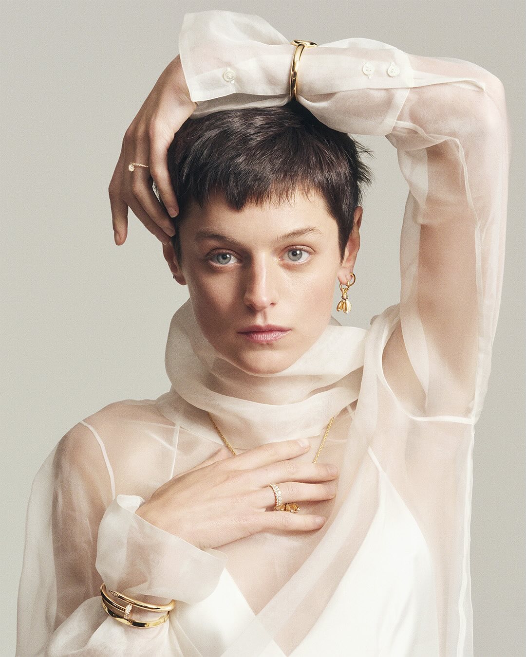 Model Emma Corrin wearing sheer white blouse and gold jewelry for Cartier Juste un Clou campaign