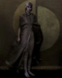 Model wearing a metallic hooded cape and pale draped garments standing before a dark textured wall with painted golden circles.