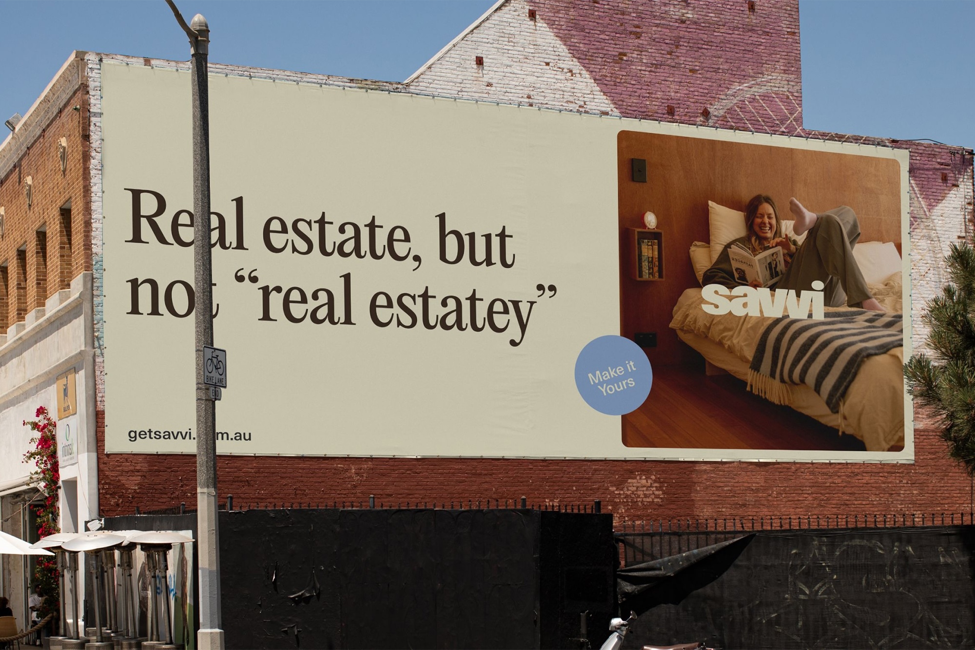Outdoor billboard advertising Savvi Real Estate mounted on a brick building exterior on a sunny day