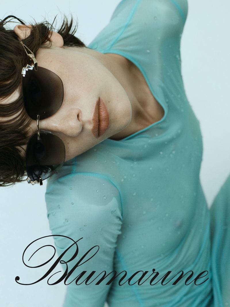 Model wearing teal mesh top and dark sunglasses against a light background for Blumarine eyewear ad campaign