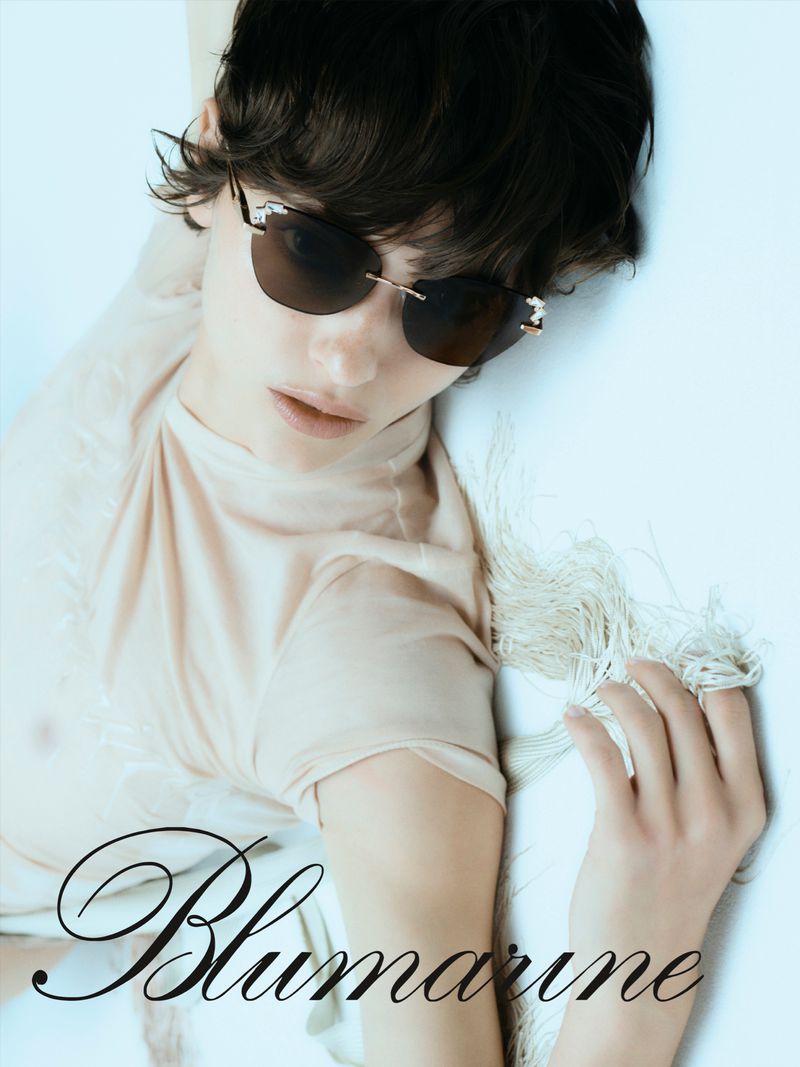 Model wearing dark sunglasses and a neutral top against a plain light background with Blumarine branding