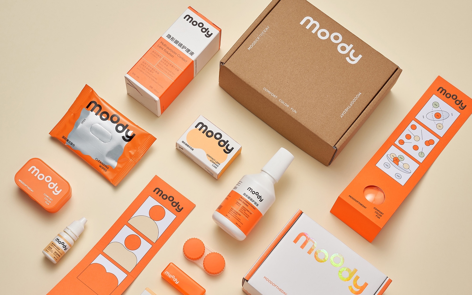 Flat lay photograph showcasing branded orange and white product packaging items arranged neatly on a neutral surface.