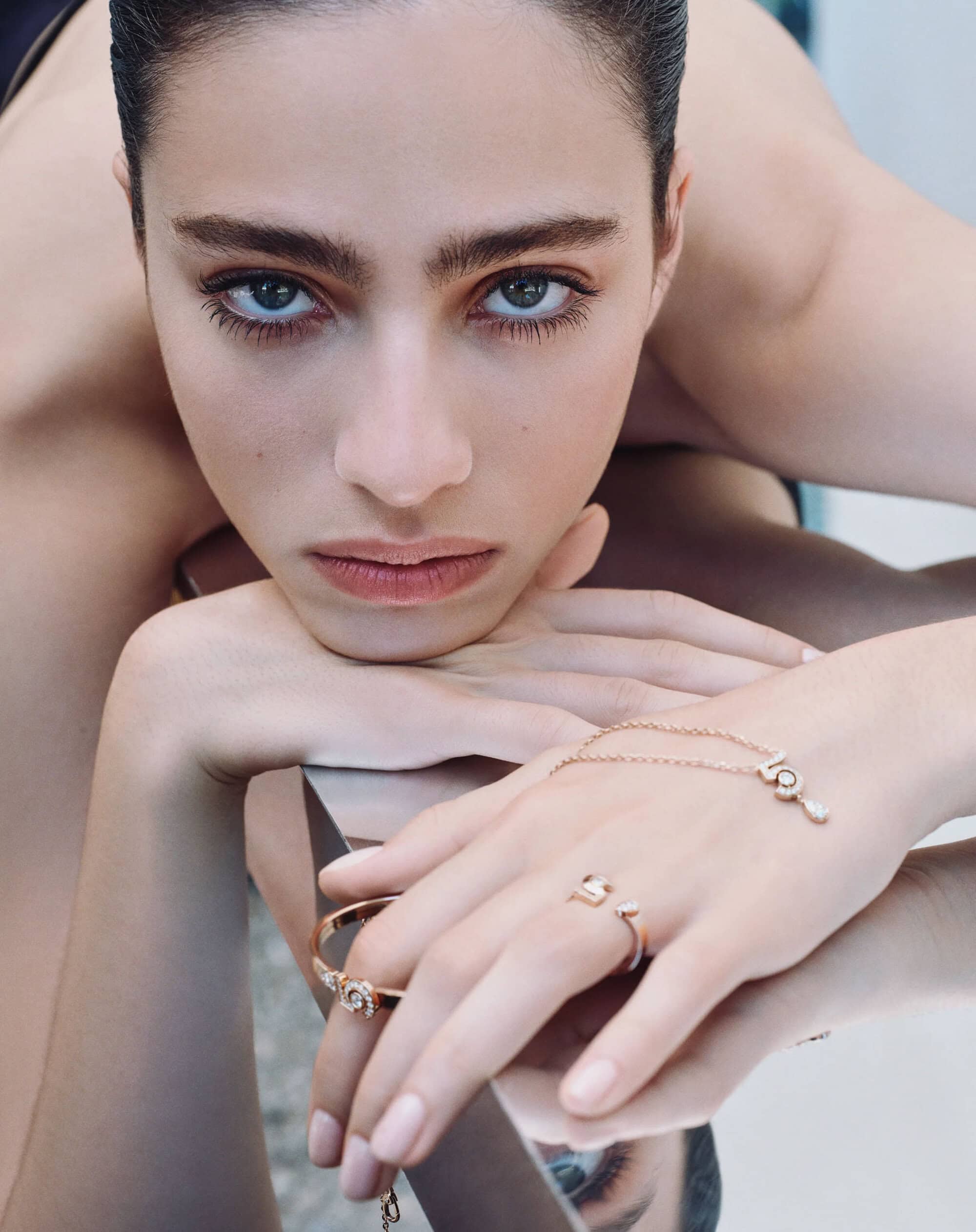Close-up portrait of a woman wearing Chanel fine jewelry including rings and a bracelet on a minimalist set