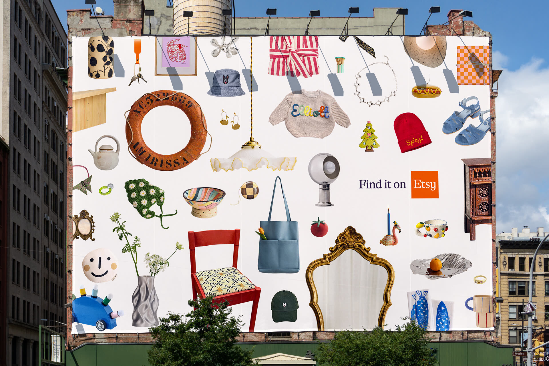 Large outdoor billboard showing a collage of diverse retail products arranged on a white background with the text Find it on Etsy