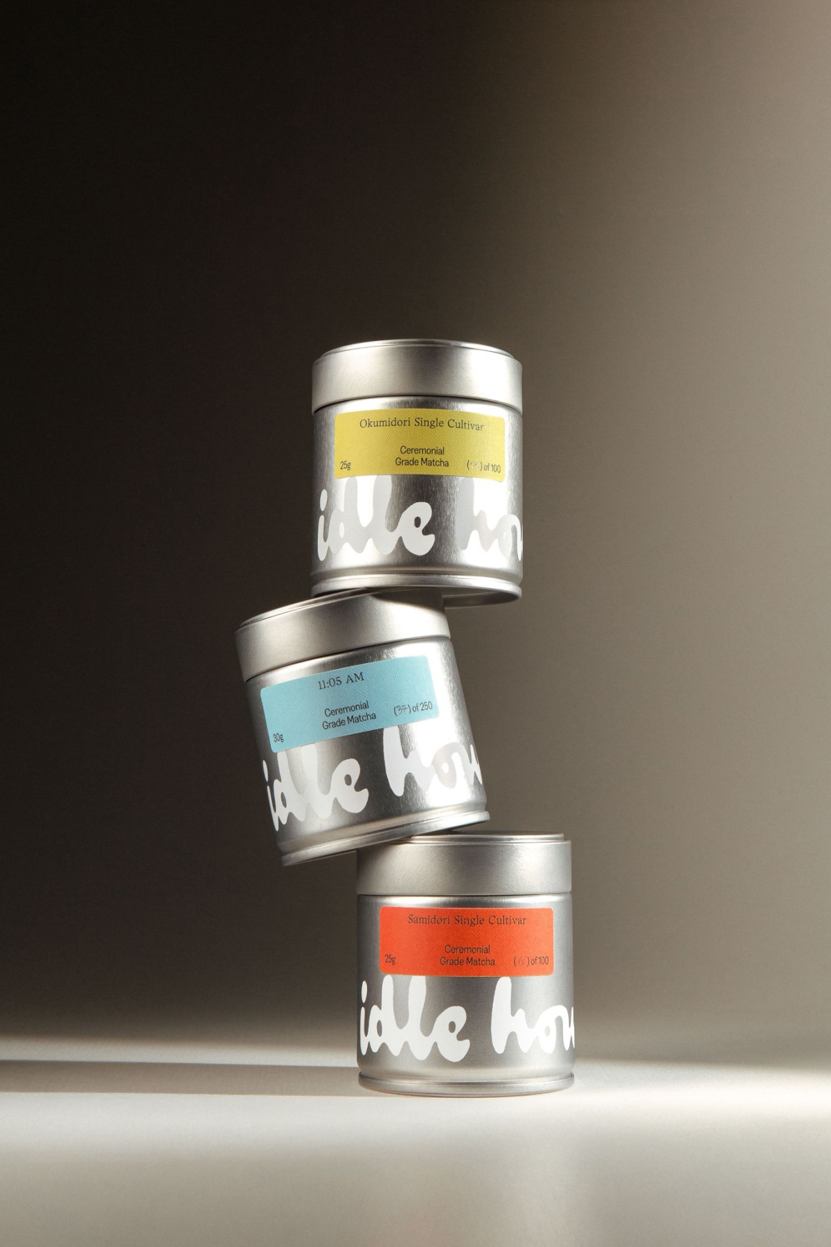 Three stacked silver metal tea tins with colorful labels against a neutral studio background