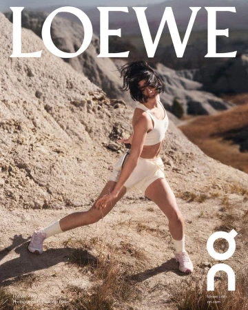 Woman in athletic top and shorts lunging dynamically in a rocky, barren landscape