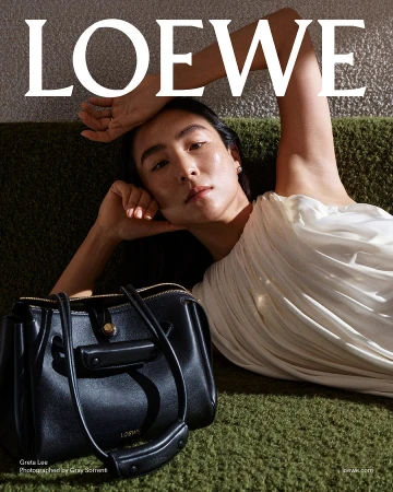 Greta Lee posing with a black leather handbag against a textured green background for the Loewe Pre-Fall 2025 ad campaign.