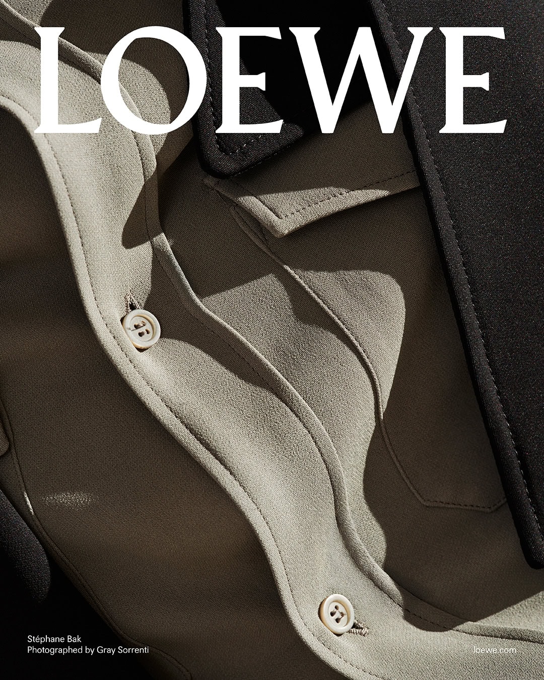 Close-up detail of a beige shirt with white buttons and a black lapel under hard sunlight for Loewe