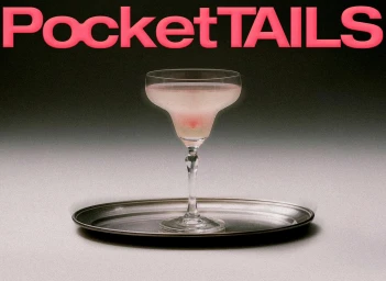 A coupe glass with a pale pink cocktail on a silver tray against a neutral backdrop with bold pink typography