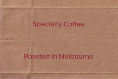 Brown kraft paper texture featuring red printed text reading Specialty Coffee and Roasted in Melbourne.