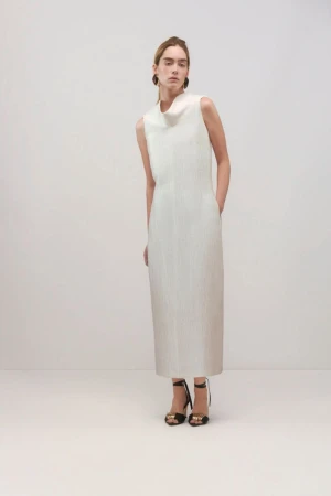Full-length shot of a woman in a sleeveless white dress with high-heeled sandals in a bright studio setting.