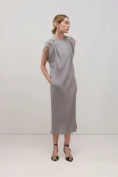 Model in grey sleeveless midi dress with gold shoulder accents standing against a plain neutral backdrop