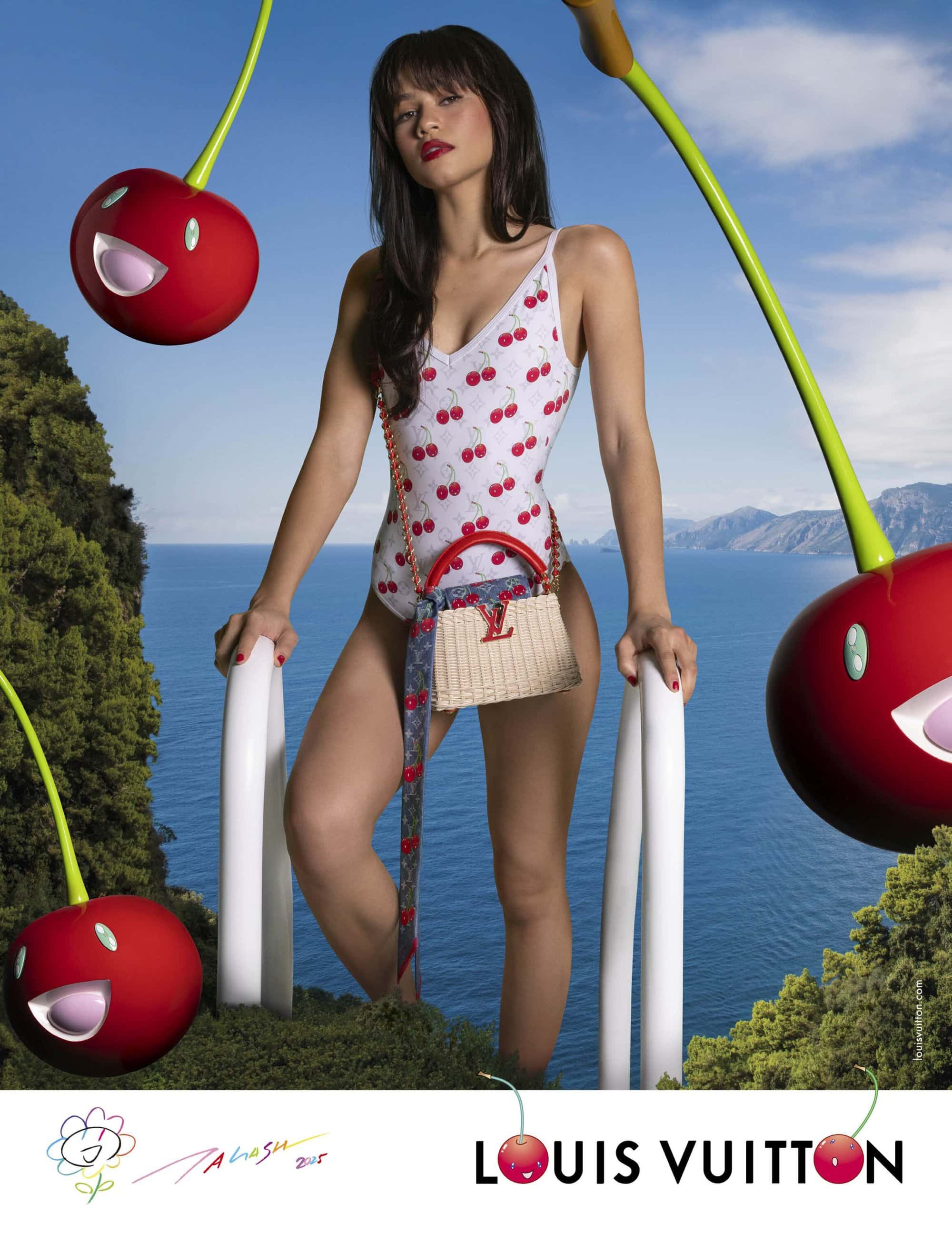 Zendaya wearing a white cherry-print swimsuit and holding a handbag in a coastal landscape with giant floating cartoon cherries.
