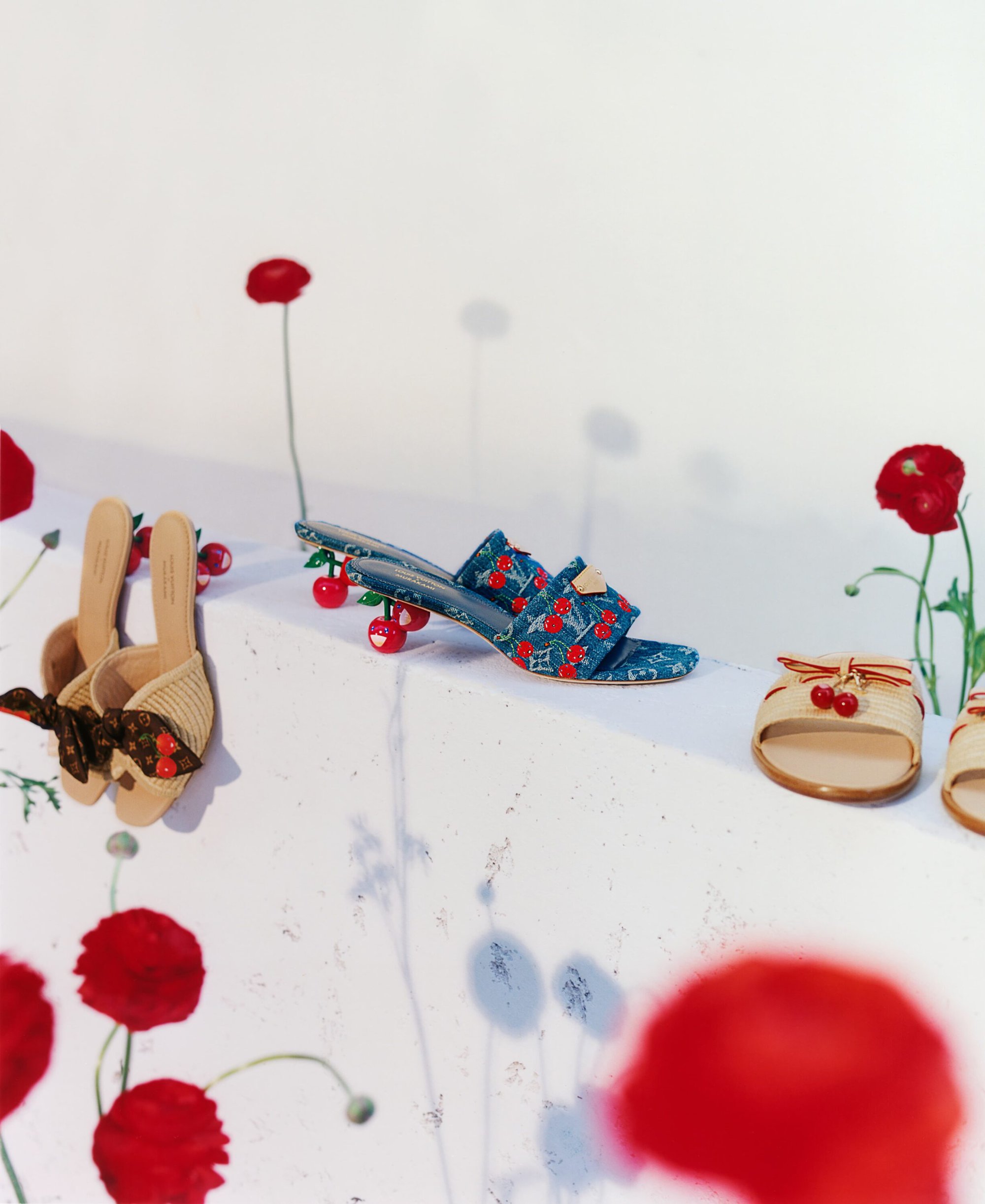 Louis Vuitton x Murakami denim and straw sandals arranged on a white surface with red poppy flowers