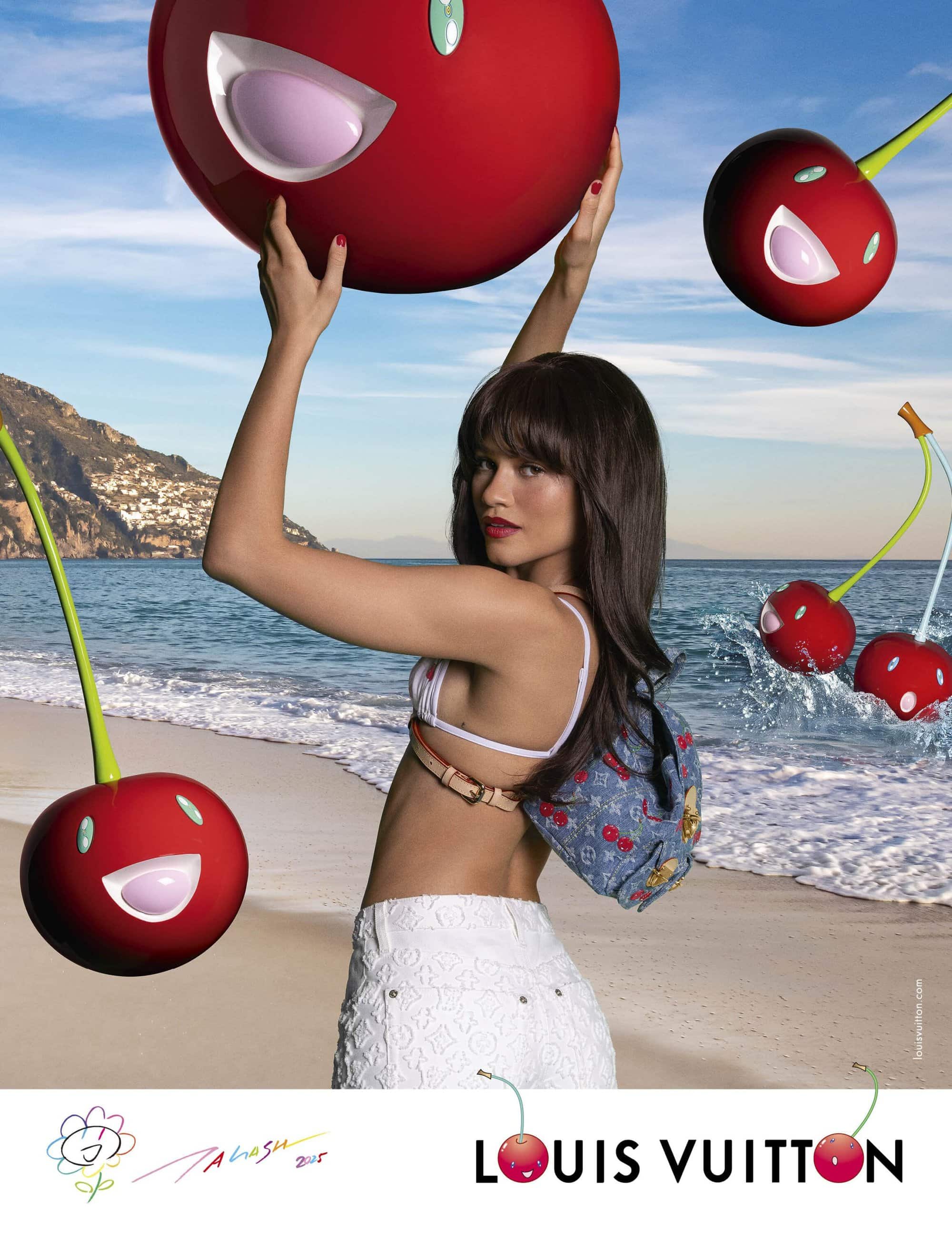 Zendaya posing on a sandy beach holding giant animated cherries for a Louis Vuitton x Murakami ad campaign.