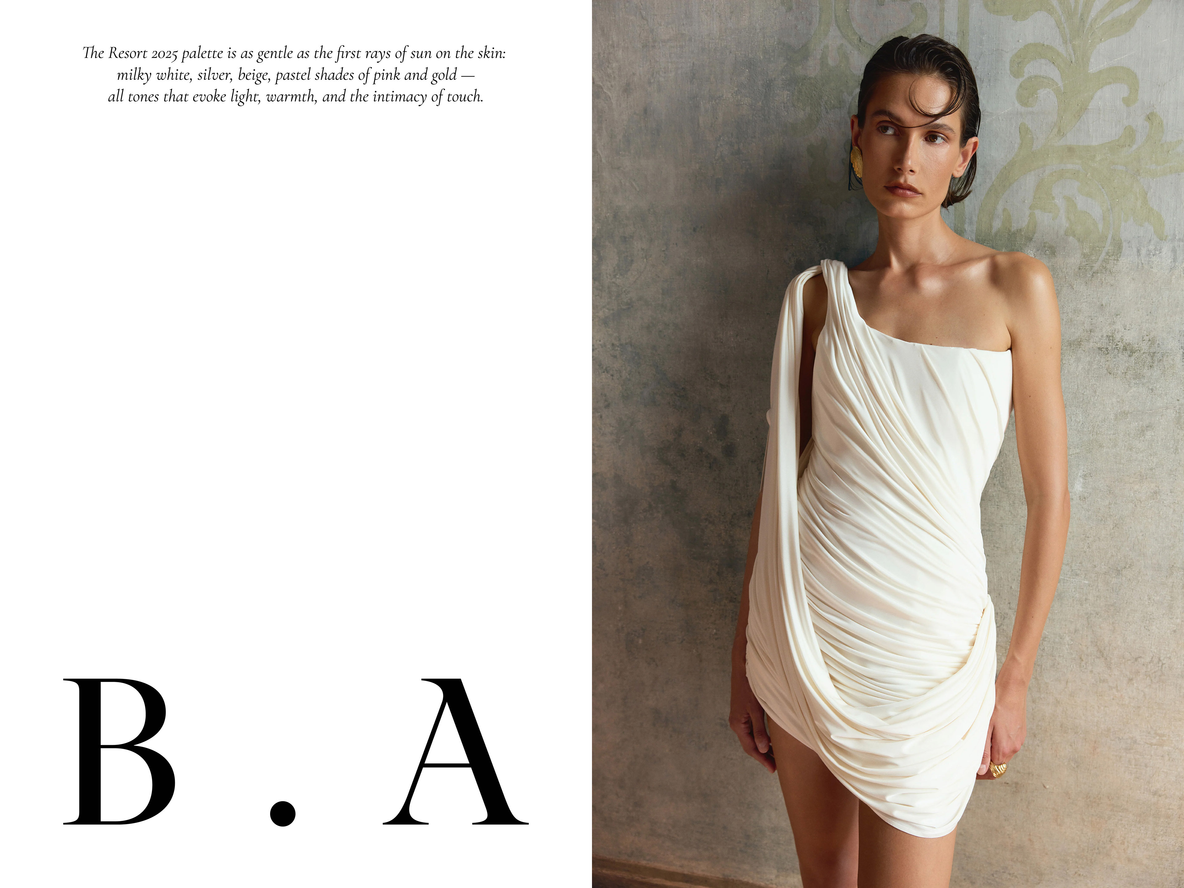 Model wearing a white draped one-shoulder dress with gold earrings against an ornate patterned wall