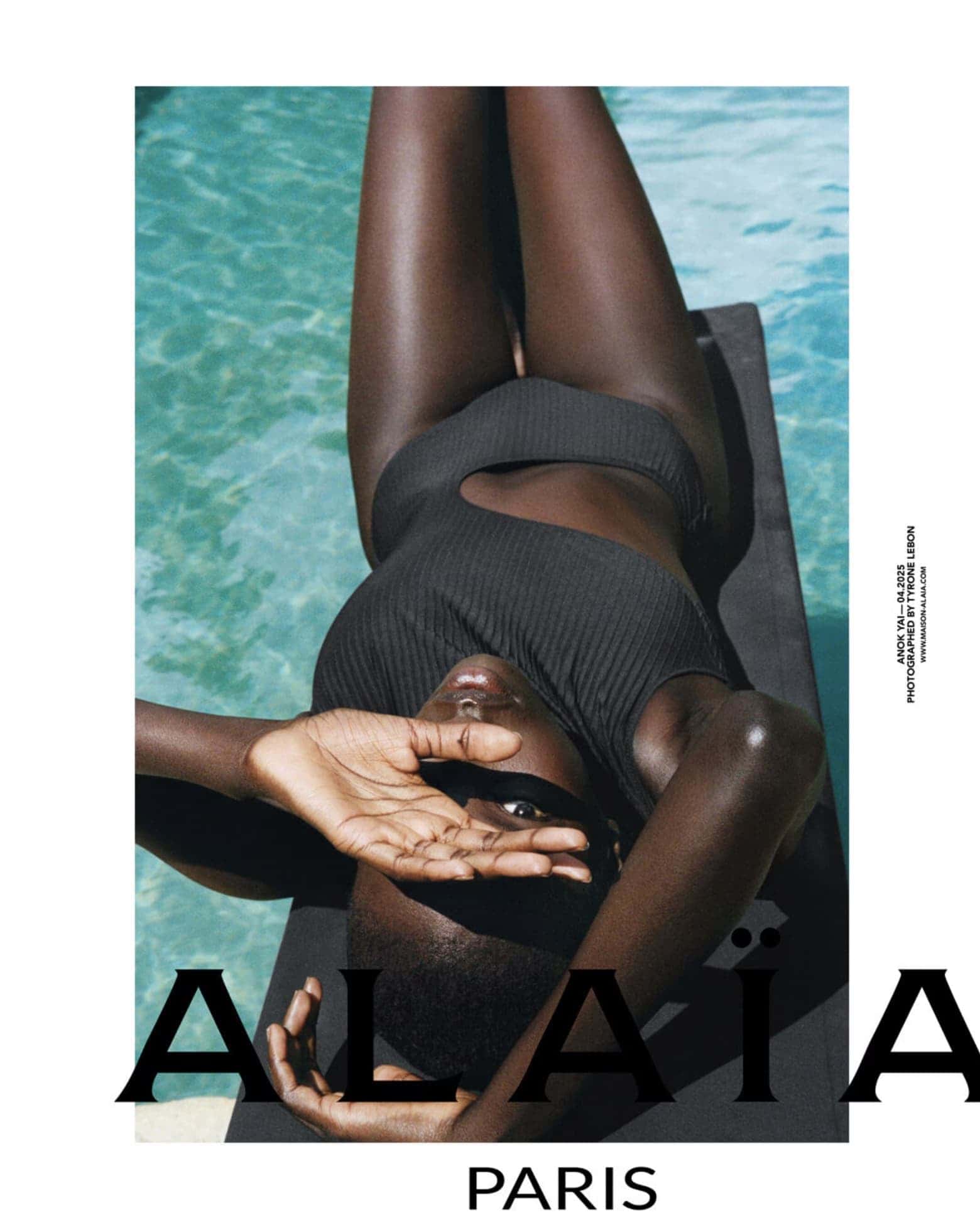 Anok Yai wearing a black swimsuit lounging by an outdoor pool for Alaïa Summer 2025 campaign