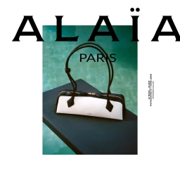 Alaia black and white leather handbag resting on a dark surface beside turquoise pool water