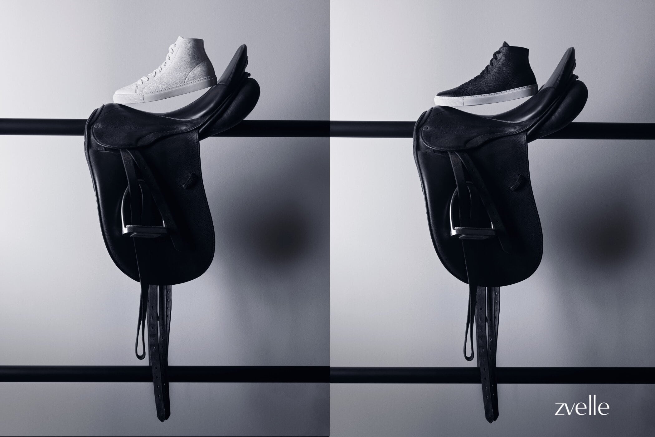 High-top sneakers resting on leather saddles mounted on a dark horizontal rail against a neutral grey wall.