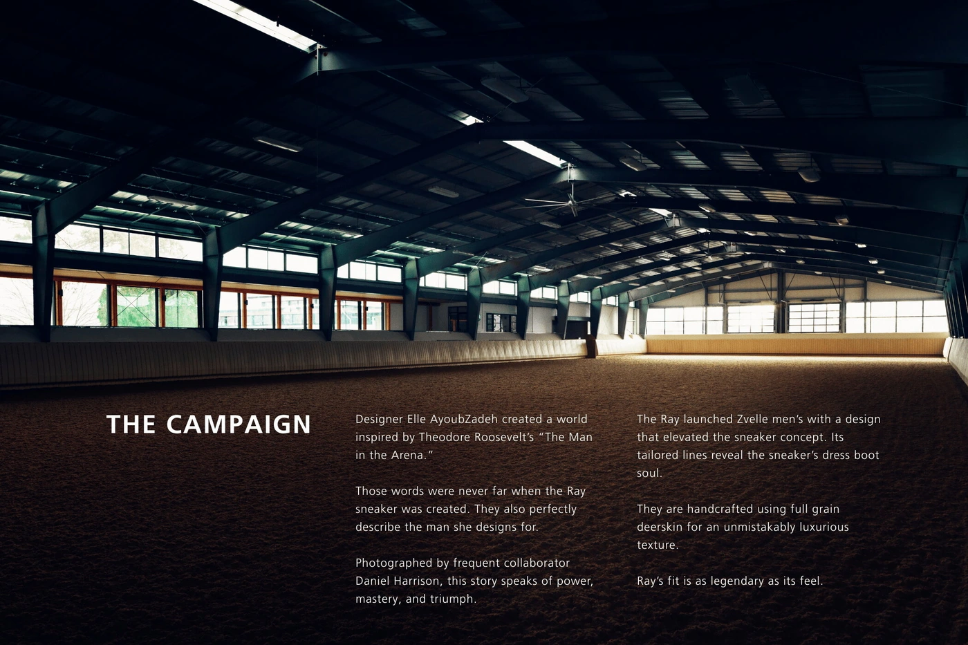Wide interior view of a large indoor riding arena with dark exposed beams and sand flooring for Zvelle Spring 2025 ad campaign.