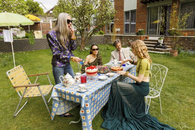 Group of people dining at a garden table on a lawn for Saint Laurent An Ordinary Day campaign shot by Martin Parr