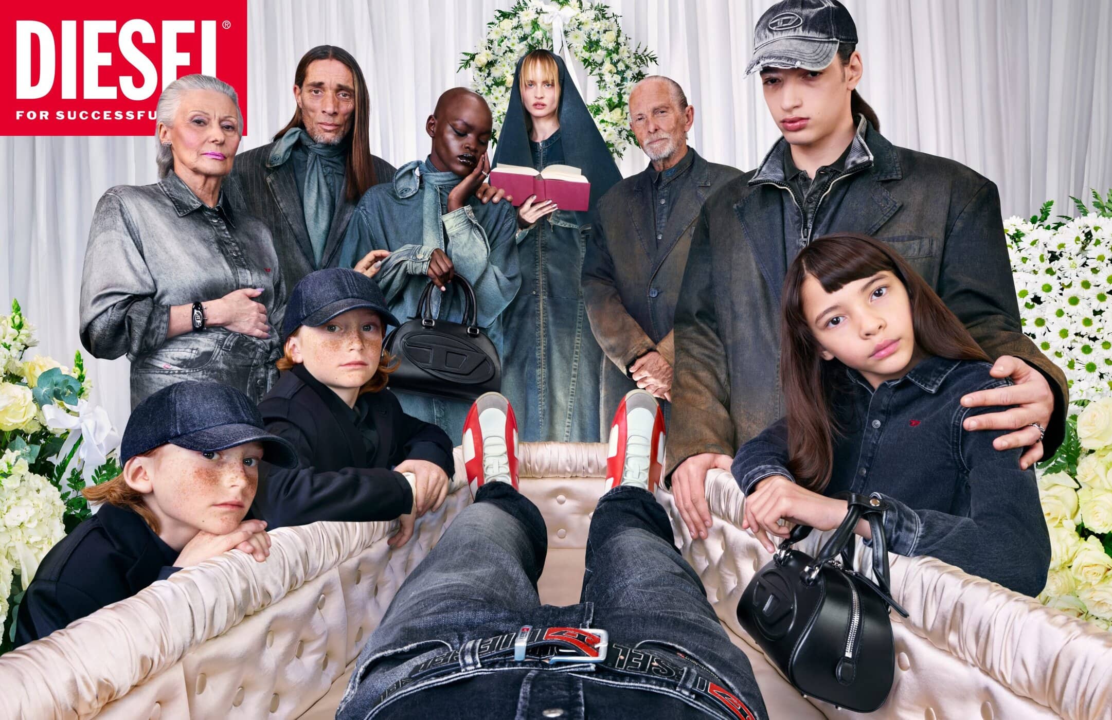 Group of diverse people standing around an open casket holding a person wearing denim jeans and a red belt for a Diesel ad campaign.