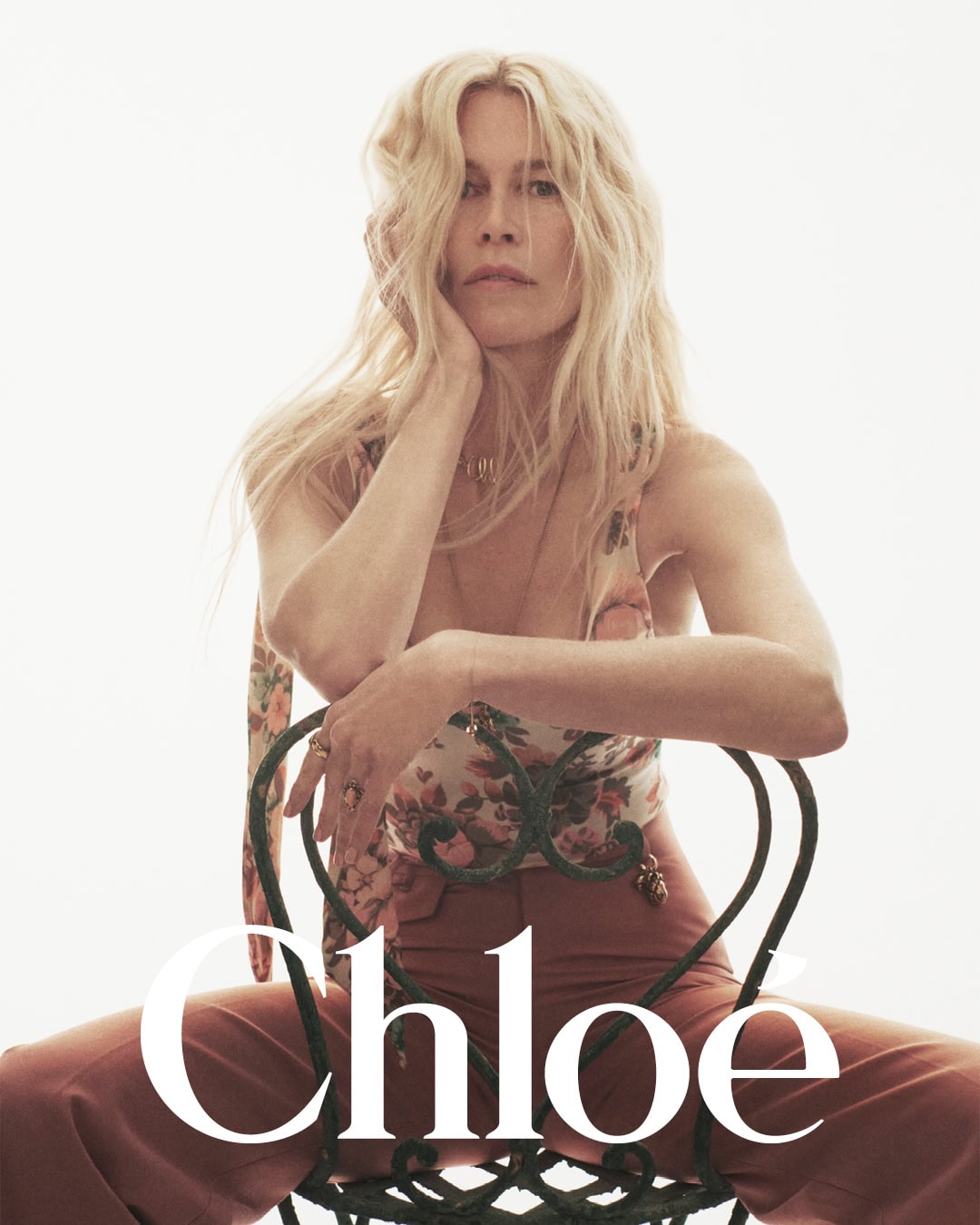 Claudia Schiffer seated on a wire chair against a white background for Chloé High Summer campaign