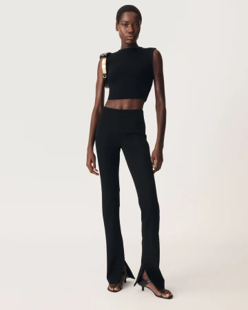 Model in black sleeveless top and flared trousers standing against white seamless background for Zara 50 Years 50 Icons campaign