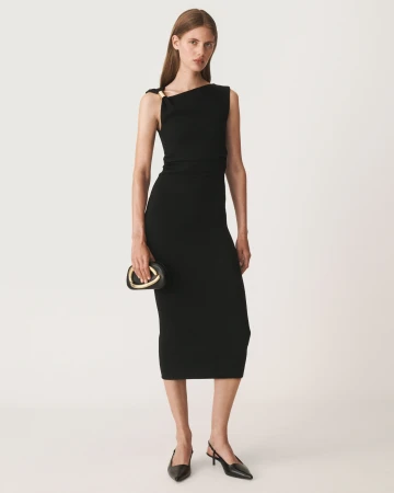Full-length portrait of a female model wearing a black sleeveless midi dress against a plain neutral background.