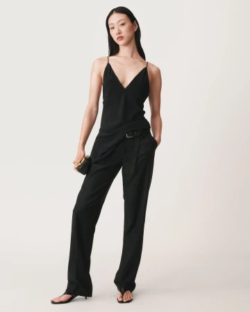 Asian female model wearing a black slip top and trousers holding a clutch against a white background for Zara campaign