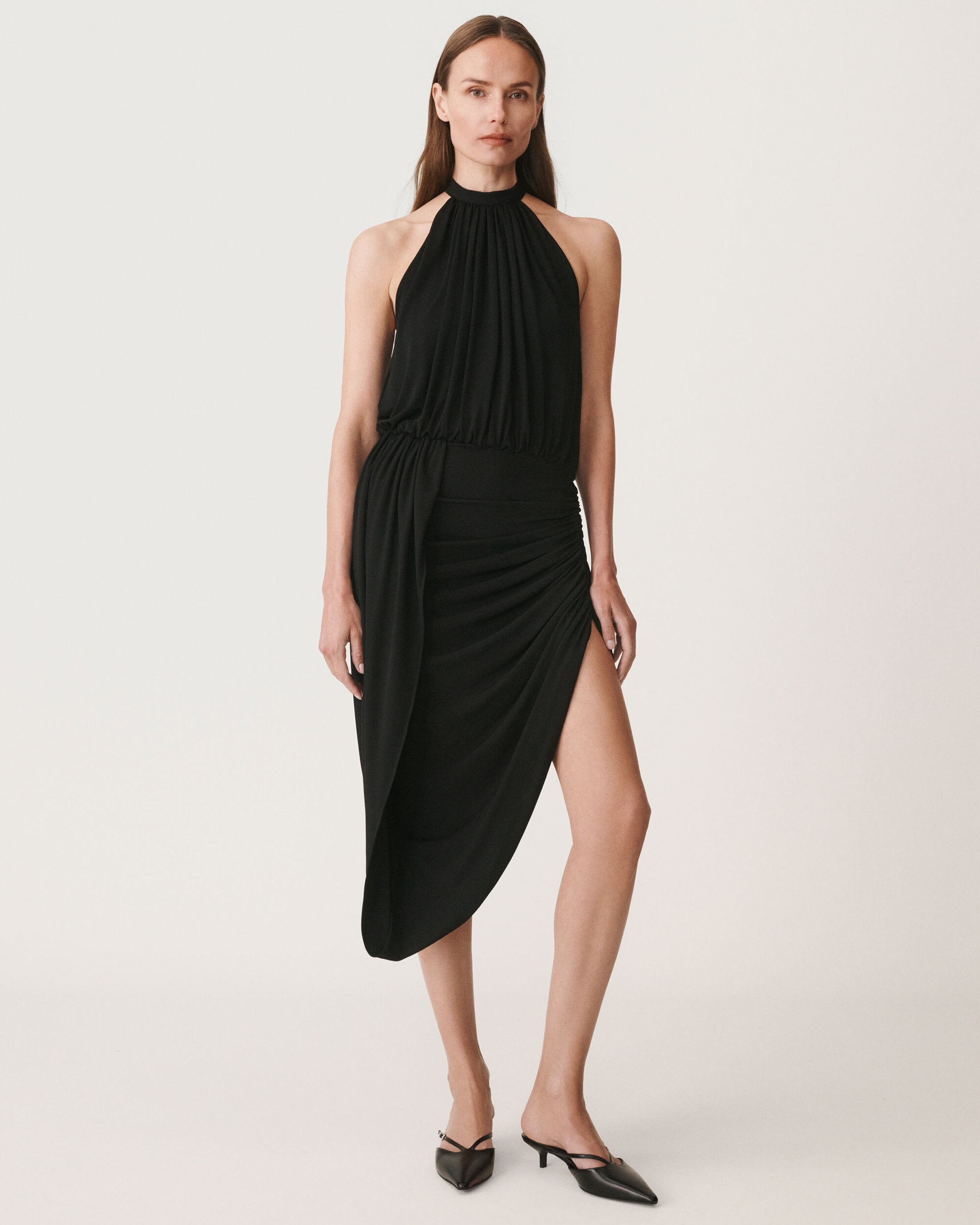 Model in black halterneck midi dress against a plain white background