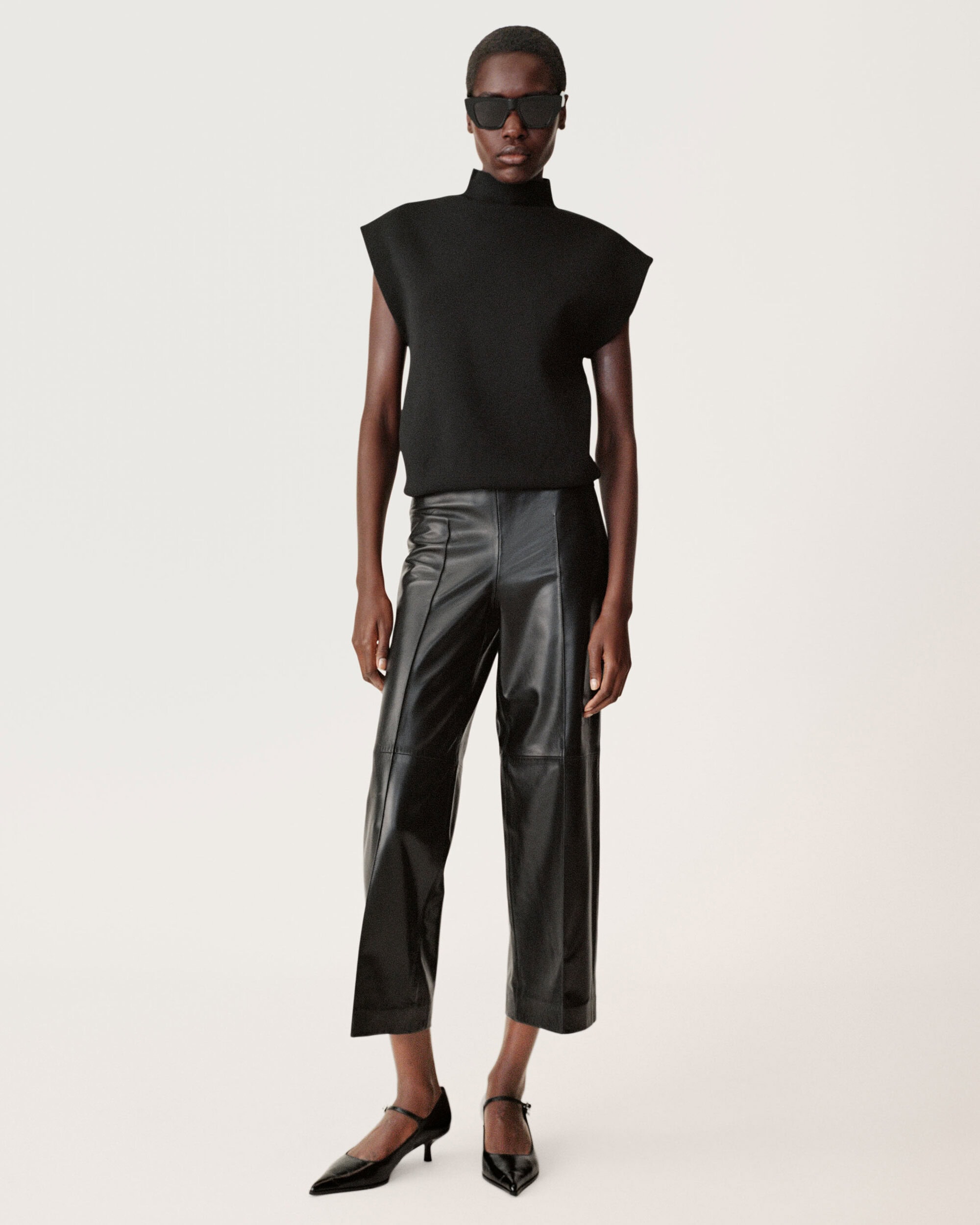Model wearing a black sleeveless top, leather pants, and sunglasses against a seamless white background for Zara.