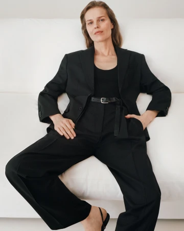 Model Eva Herzigova in a black suit seated on a white sofa for the Zara 50 Years 50 Icons campaign photographed by Steven Meisel.